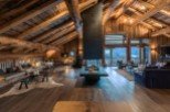 Luxury chalet with stunning mountain views and a large, open-plan living area featuring a dramatic fireplace.