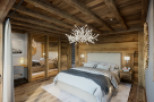 Luxurious chalet bedroom with stunning wood-beamed ceiling and antler chandelier.