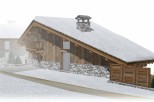 This stunning chalet boasts a unique architectural design, featuring a sloped roof covered in snow, exposed wooden beams, and a stone chimney.