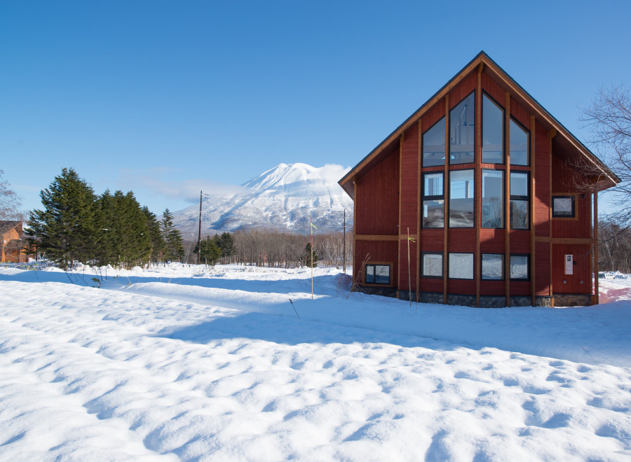 This stunning A-frame cabin boasts a wall of windows showcasing breathtaking mountain views, perfect for a cozy winter getaway.