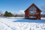 This stunning A-frame cabin boasts a wall of windows showcasing breathtaking mountain views, perfect for a cozy winter getaway.