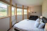 Experience tranquility in this stunning bedroom, featuring expansive windows that frame breathtaking views of the surrounding landscape.