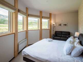 Experience tranquility in this stunning bedroom, featuring expansive windows that frame breathtaking views of the surrounding landscape.