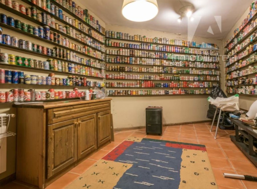 Explore this unique property featuring a remarkable collection of beer cans displayed on shelves throughout the room.