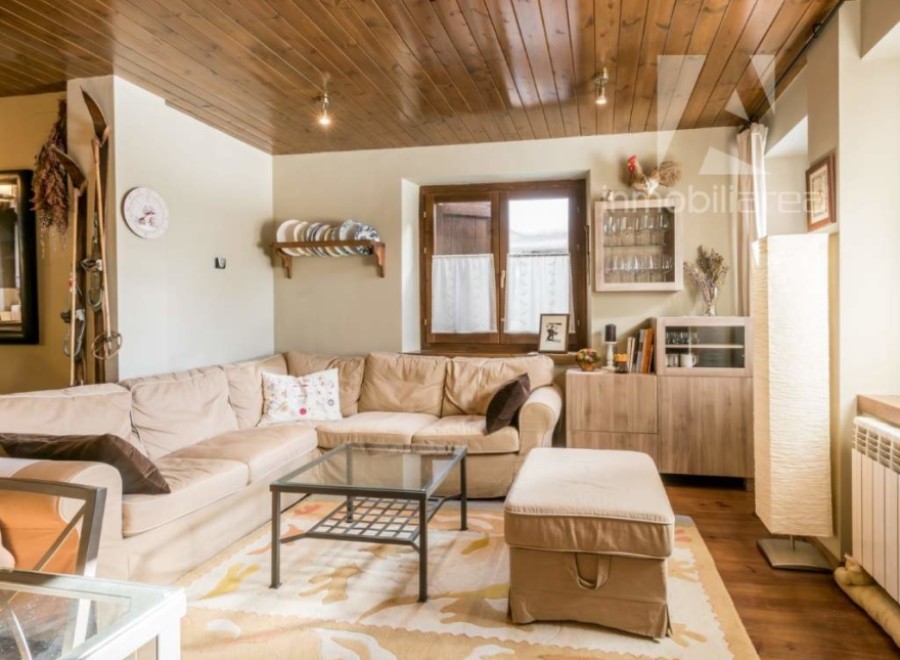 This cozy living room features a warm, inviting atmosphere with its wooden ceiling and comfortable seating.