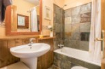 Discover the charm of this bathroom, featuring a stylish pedestal sink and a cozy wooden paneling.