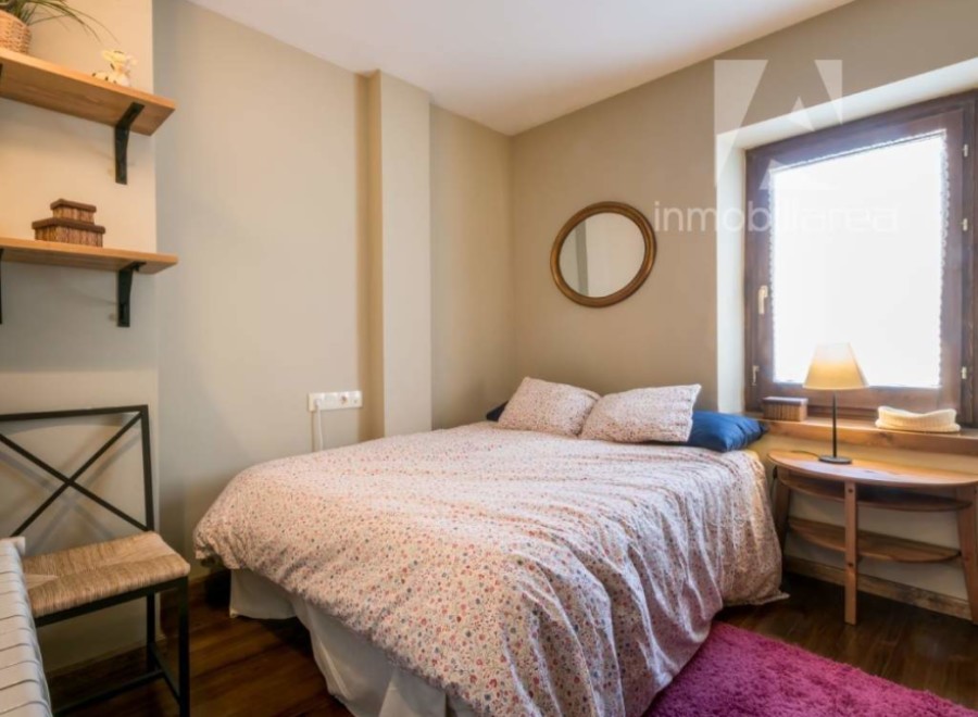 Cozy bedroom with a charming floral bedspread and a round mirror adding a touch of elegance.