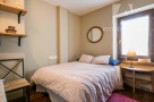 Cozy bedroom with a charming floral bedspread and a round mirror adding a touch of elegance.
