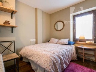 Cozy bedroom with a charming floral bedspread and a round mirror adding a touch of elegance.