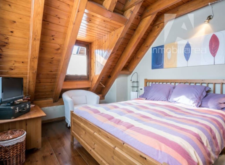 Discover the charm of this cozy bedroom with its unique wooden ceiling and inviting ambiance.
