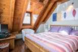 Discover the charm of this cozy bedroom with its unique wooden ceiling and inviting ambiance.