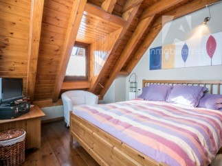 Discover the charm of this cozy bedroom with its unique wooden ceiling and inviting ambiance.