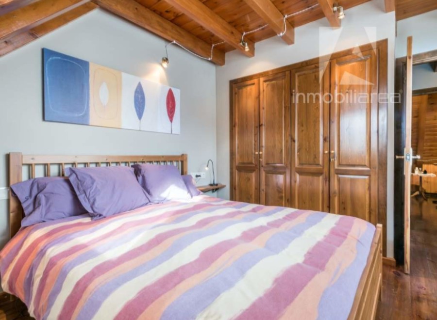 Discover a cozy bedroom with a charming wooden ceiling and a comfortable bed.