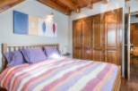 Discover a cozy bedroom with a charming wooden ceiling and a comfortable bed.