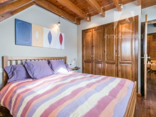 Discover a cozy bedroom with a charming wooden ceiling and a comfortable bed.