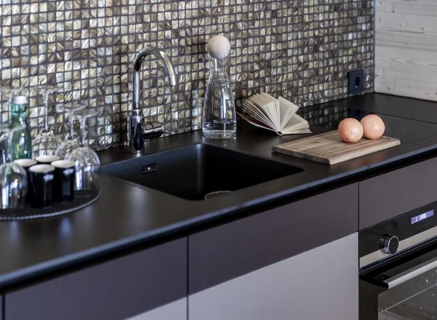 Discover a modern kitchen with sleek black countertops and a stylish backsplash.