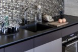 Discover a modern kitchen with sleek black countertops and a stylish backsplash.
