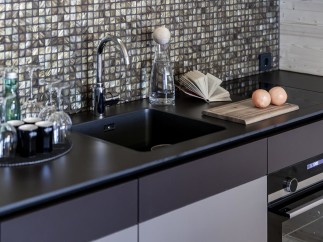 Discover a modern kitchen with sleek black countertops and a stylish backsplash.
