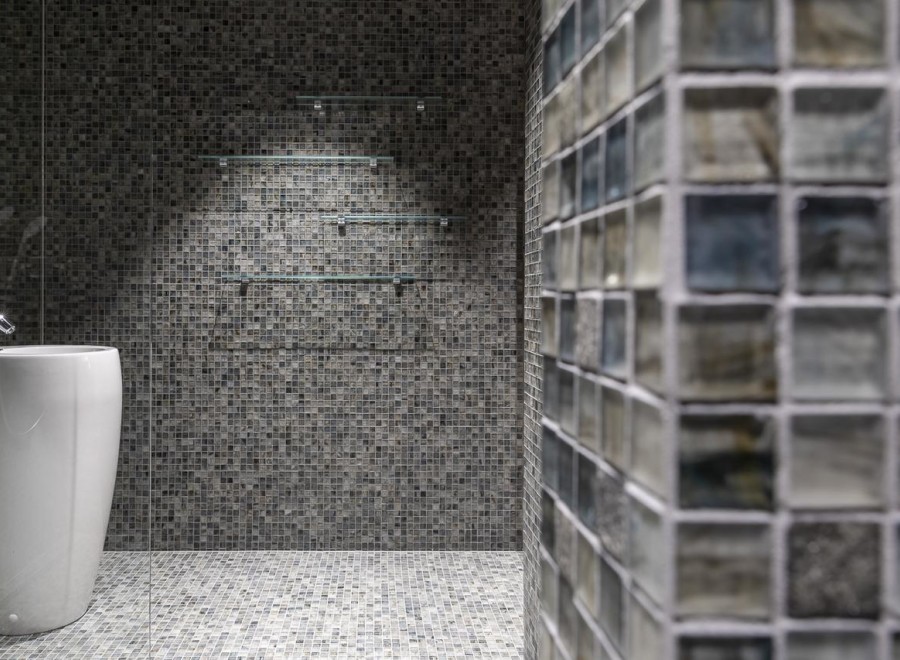 This modern bathroom features a sleek, pedestal sink and a stunning mosaic tile design.