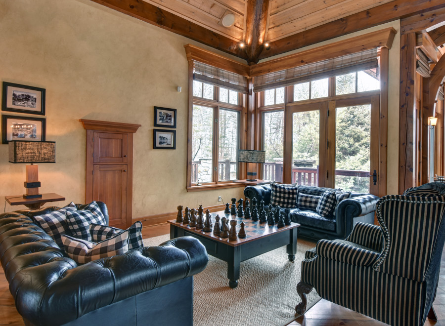 This luxurious living room boasts a cozy ambiance with its wooden ceiling and large windows.