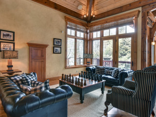 This luxurious living room boasts a cozy ambiance with its wooden ceiling and large windows.