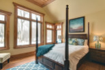 This cozy bedroom features a beautiful four-poster bed and a stunning view of the winter landscape through large windows.