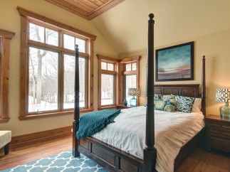 This cozy bedroom features a beautiful four-poster bed and a stunning view of the winter landscape through large windows.