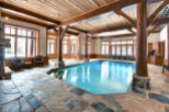 This luxurious indoor pool area boasts a stunning wooden ceiling and exposed beams, creating a warm and inviting atmosphere.