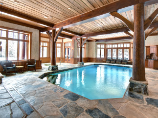 This luxurious indoor pool area boasts a stunning wooden ceiling and exposed beams, creating a warm and inviting atmosphere.