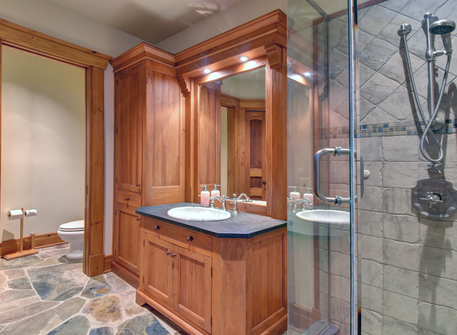 This luxurious bathroom features a custom wooden vanity with a sleek black countertop and a stylish sink.