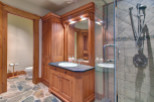 This luxurious bathroom features a custom wooden vanity with a sleek black countertop and a stylish sink.