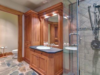 This luxurious bathroom features a custom wooden vanity with a sleek black countertop and a stylish sink.
