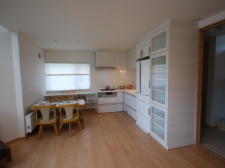 This bright and airy kitchen features modern white cabinetry and appliances, creating a clean and inviting space.