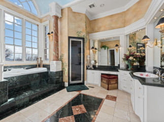 Indulge in luxury within this exquisite bathroom, featuring a stunning marble tub and countertops.
