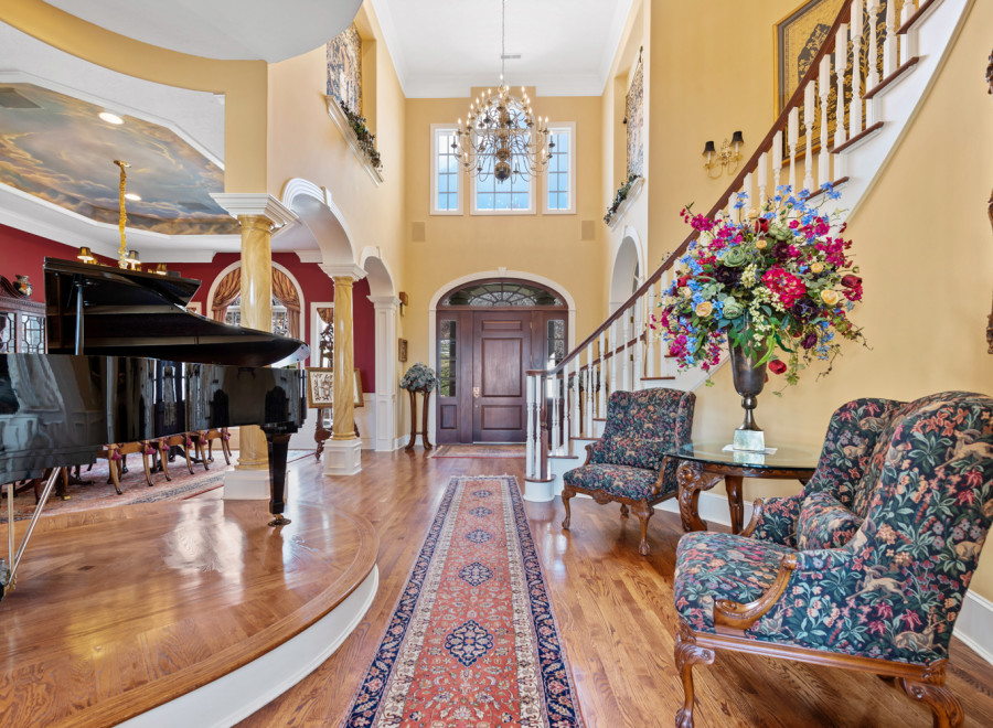 Step into luxury with this stunning property! The grand foyer welcomes you with a beautiful piano, elegant staircase, and exquisite floral arrangements.