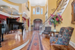 Step into luxury with this stunning property! The grand foyer welcomes you with a beautiful piano, elegant staircase, and exquisite floral arrangements.