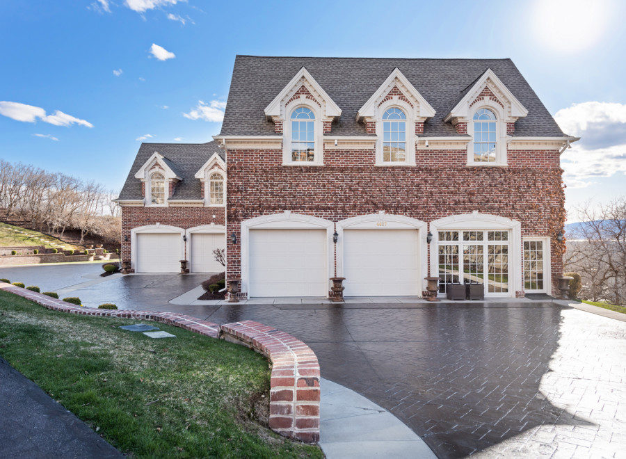 Stunning brick home with a grand facade, featuring multiple garage doors and elegant arched windows.
