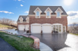 Stunning brick home with a grand facade, featuring multiple garage doors and elegant arched windows.
