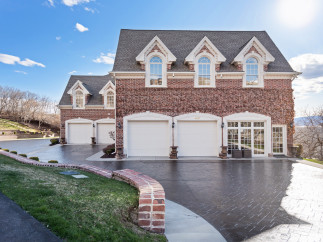 Stunning brick home with a grand facade, featuring multiple garage doors and elegant arched windows.