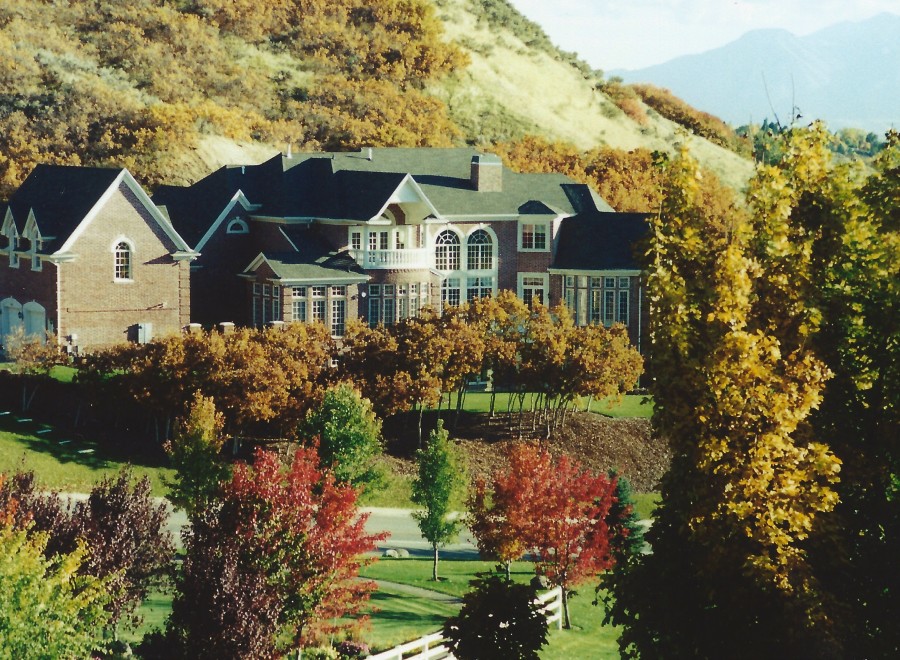 This stunning property showcases a grand brick mansion nestled amidst a vibrant autumn landscape.