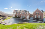 Stunning brick estate with a grand design, featuring a circular driveway and lush green landscaping.