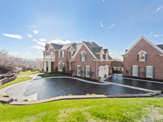 Stunning brick estate with a grand design, featuring a circular driveway and lush green landscaping.