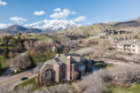 Stunning aerial view of a luxurious brick home nestled in a picturesque mountain setting.