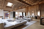 Experience luxury living in this stunning chalet, featuring a spacious open-plan living area with a cozy fireplace and a modern kitchen.