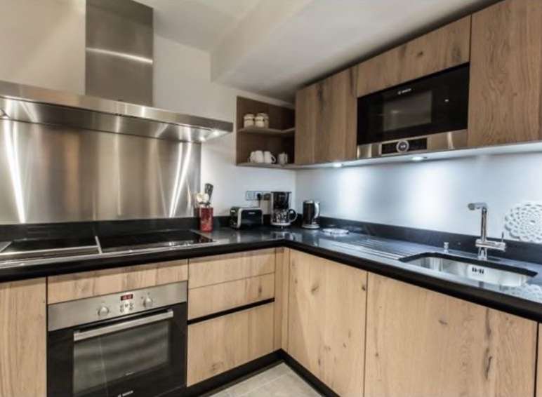 Modern kitchen with stainless steel appliances and light oak wood cabinets.