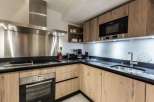 Modern kitchen with stainless steel appliances and light oak wood cabinets.