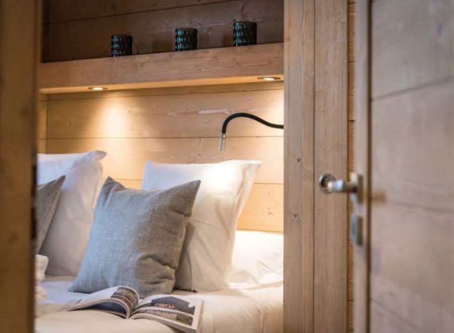 Cozy bedroom with built-in wooden shelving and reading lamp.