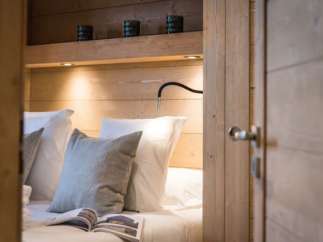 Cozy bedroom with built-in wooden shelving and reading lamp.