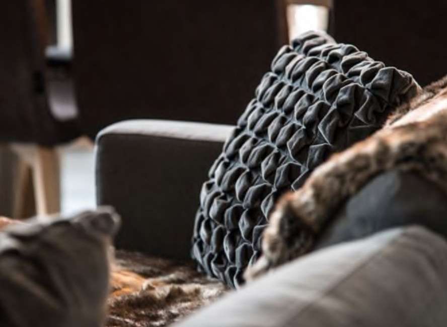 Cozy up in this luxurious living space, featuring plush gray velvet pillows and a soft faux fur throw.