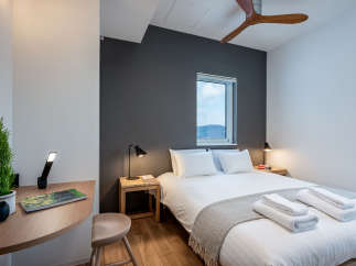 This cozy bedroom features a comfortable double bed with crisp white linens and a soft gray throw, perfect for a relaxing stay.